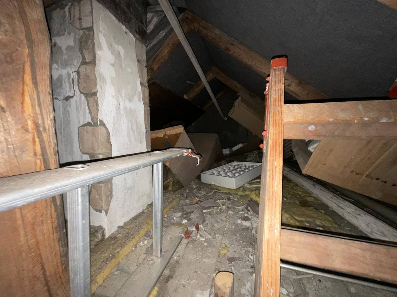 Dachboden mit Holzbalken, Leiter und Kartons vor der Entrümpelung