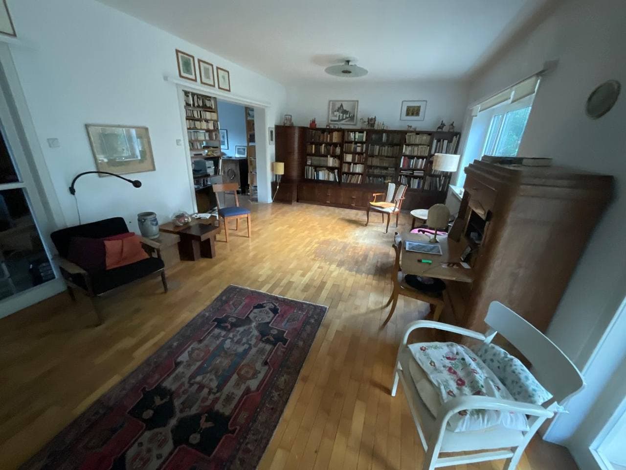 Wohnzimmer mit Bücherregal, Sesseln und Holzmöbeln vor der Haushaltsauflösung